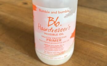 Bumble and Bumble Haipressserin näkymätön öljy ja UV -pohjamaalin suoja, valkoinen pullo, jossa on aerosolin yläosa, istuu puisella pöydällä