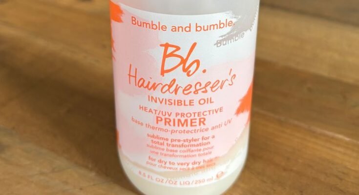 Bumble and Bumble Haipressserin näkymätön öljy ja UV -pohjamaalin suoja, valkoinen pullo, jossa on aerosolin yläosa, istuu puisella pöydällä