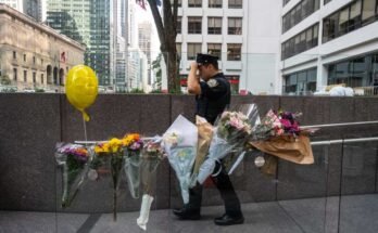 New York, New York - 29. heinäkuuta: New Yorkin poliisi kulkee puolivälissä sijaitsevan toimistorakennuksen edessä sijaitsevien kukien edessä, jossa aseellinen mies tappoi neljä ihmistä 29. heinäkuuta 2025 New Yorkissa. (Kuva: Stephanie Keith / Getty Images)