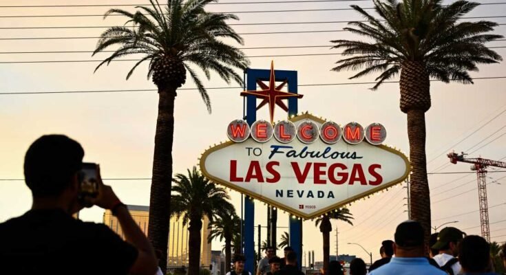 Ihmiset ottavat valokuvia Fabulous Las Vegas -paneelin vastaanotolla sumuisen oranssin taivaan alla, kun aurinko laskee 29. heinäkuuta 2023.