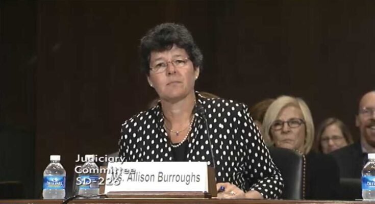 Tässä kuvakaappauksessa Allison Burroughs sijaitsee pöydässä, joka on varustettu mikrofonilla senaatin vahvistusyleisönsä aikana vuonna 2014 tullakseen amerikkalaiseksi käräjätuomariksi.